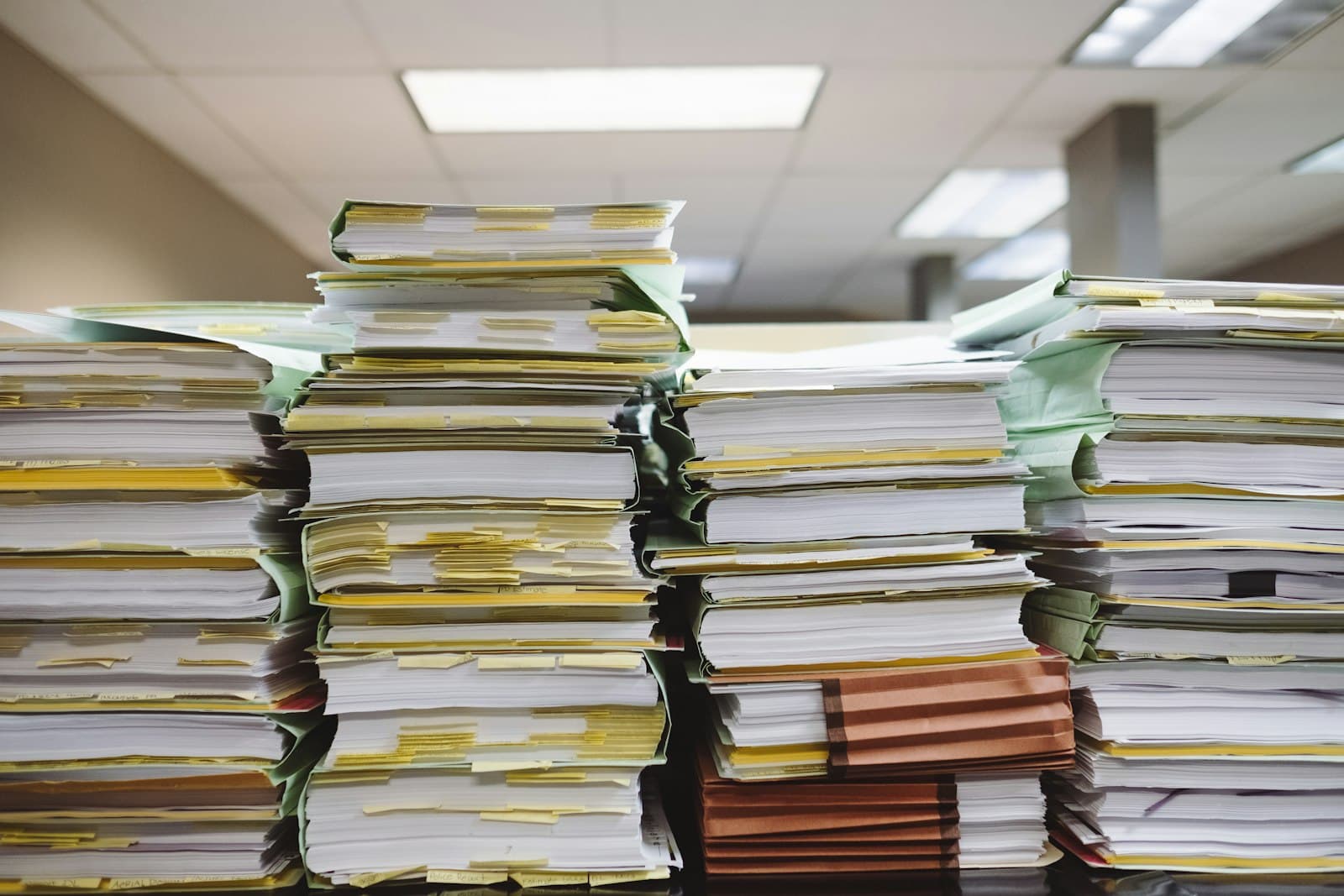 Stacks of organized paper documents and labelled file folders on a desk